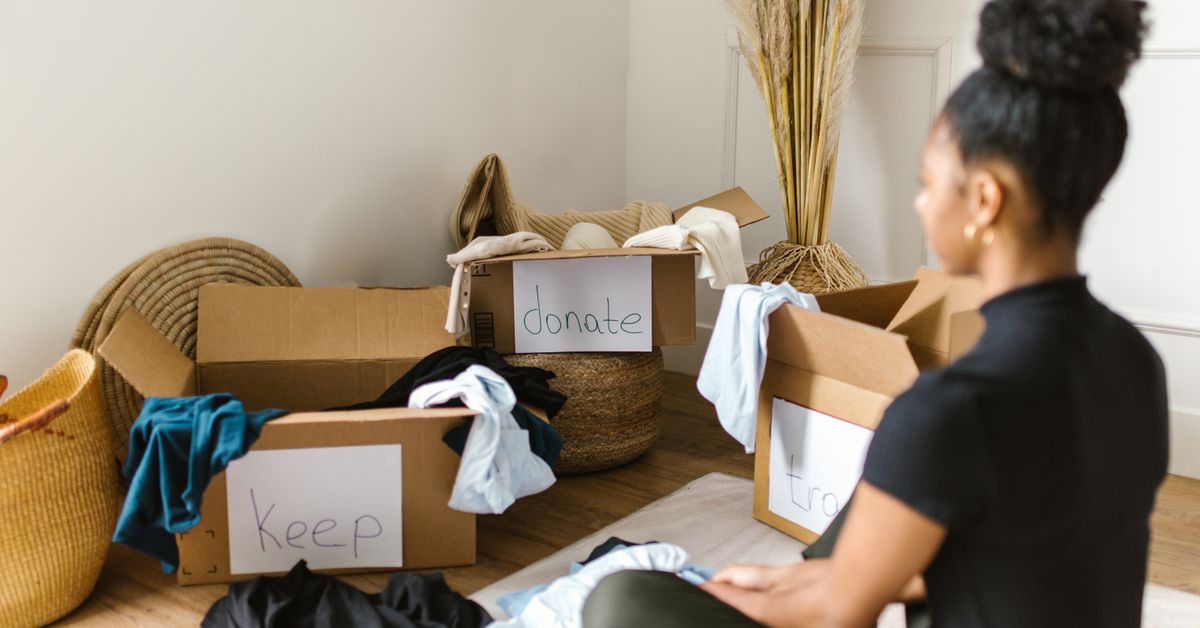 Separando roupas para doação Mulher separando roupas em caixas para doar e manter