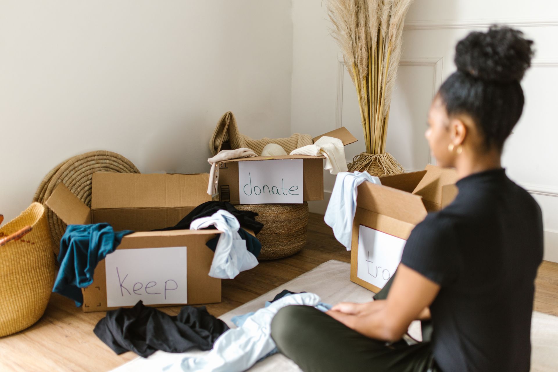 Woman sitting in front of cardboard boxes sorting clothes for donation