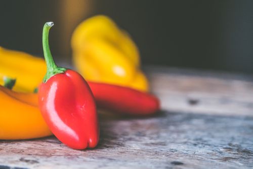 Free Vibrant red and yellow bell peppers on a rustic wooden table, showcasing fresh and healthy ingredients. Stock Photo