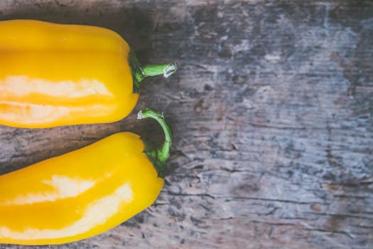 Close-up of fresh yellow peppers on a rustic wooden table, showcasing vibrant color contrast.