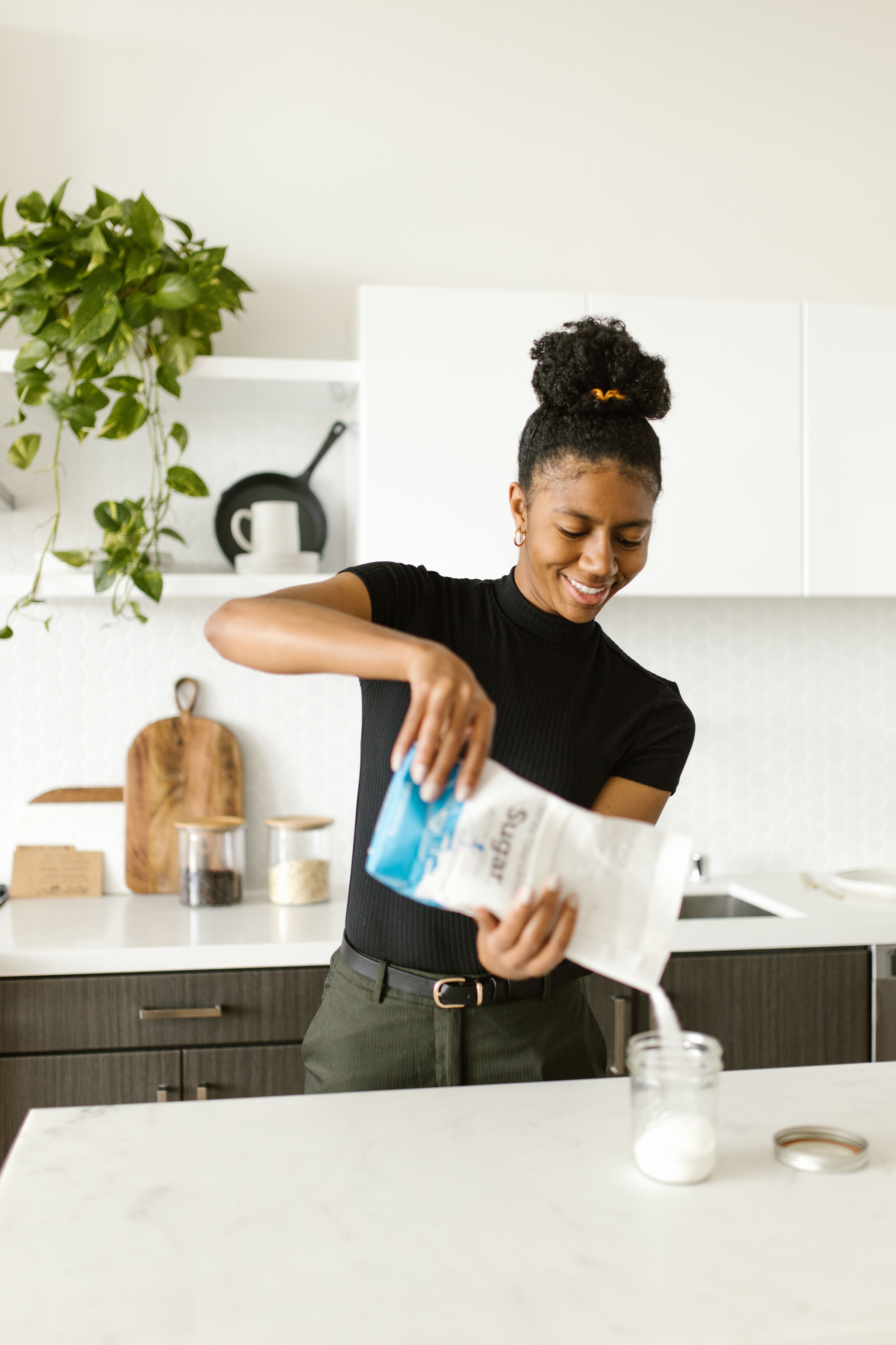 A Woman Pouring Sugar on a Glass Container · Free Stock Photo