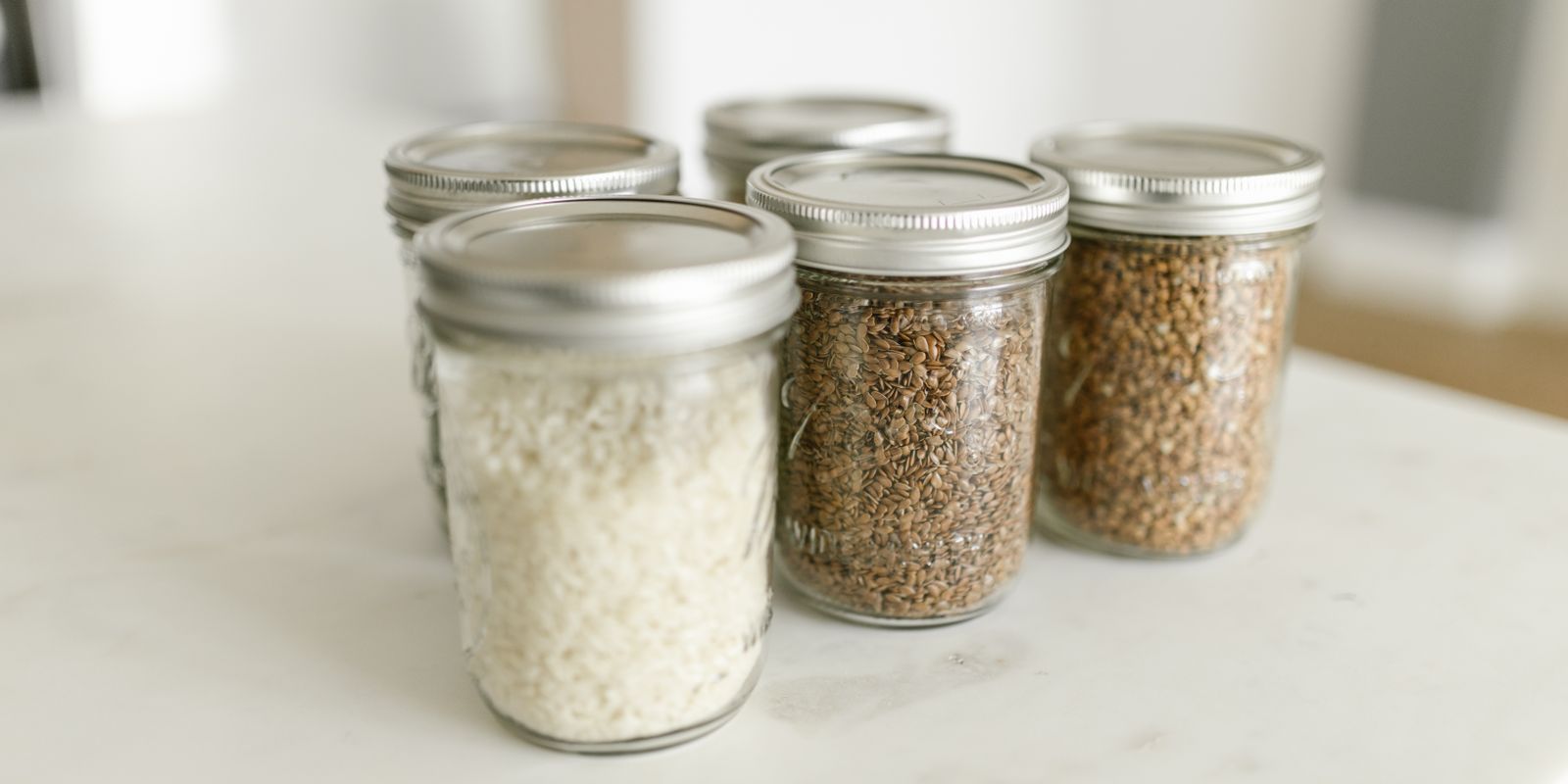 Close-up of glass jars filled with rice and grains on a kitchen counter, ideal for storage.