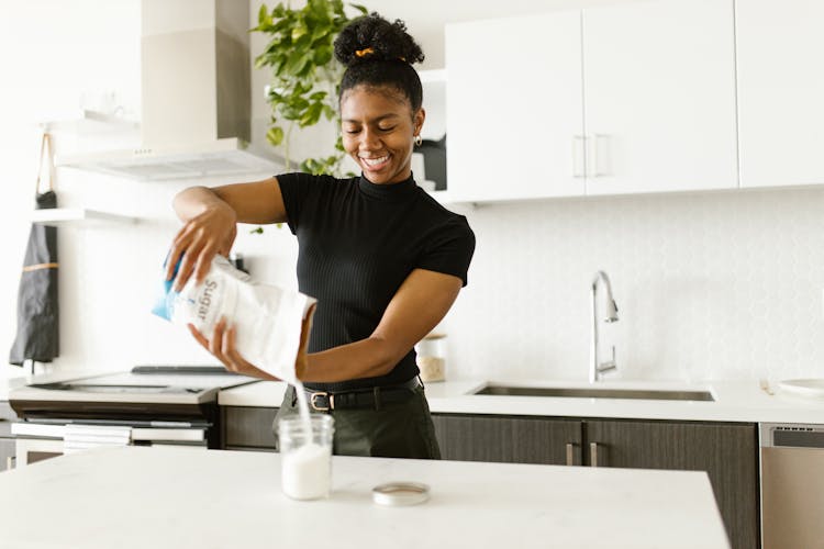 Woman Pouring Sugar On A Glass Container 