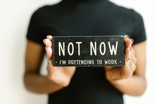 Close-up of a woman holding a humorous office sign, perfect for workplace decor.