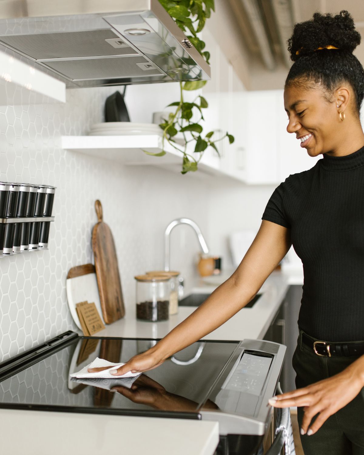 Professional cleaner in black wiping down a kitchen