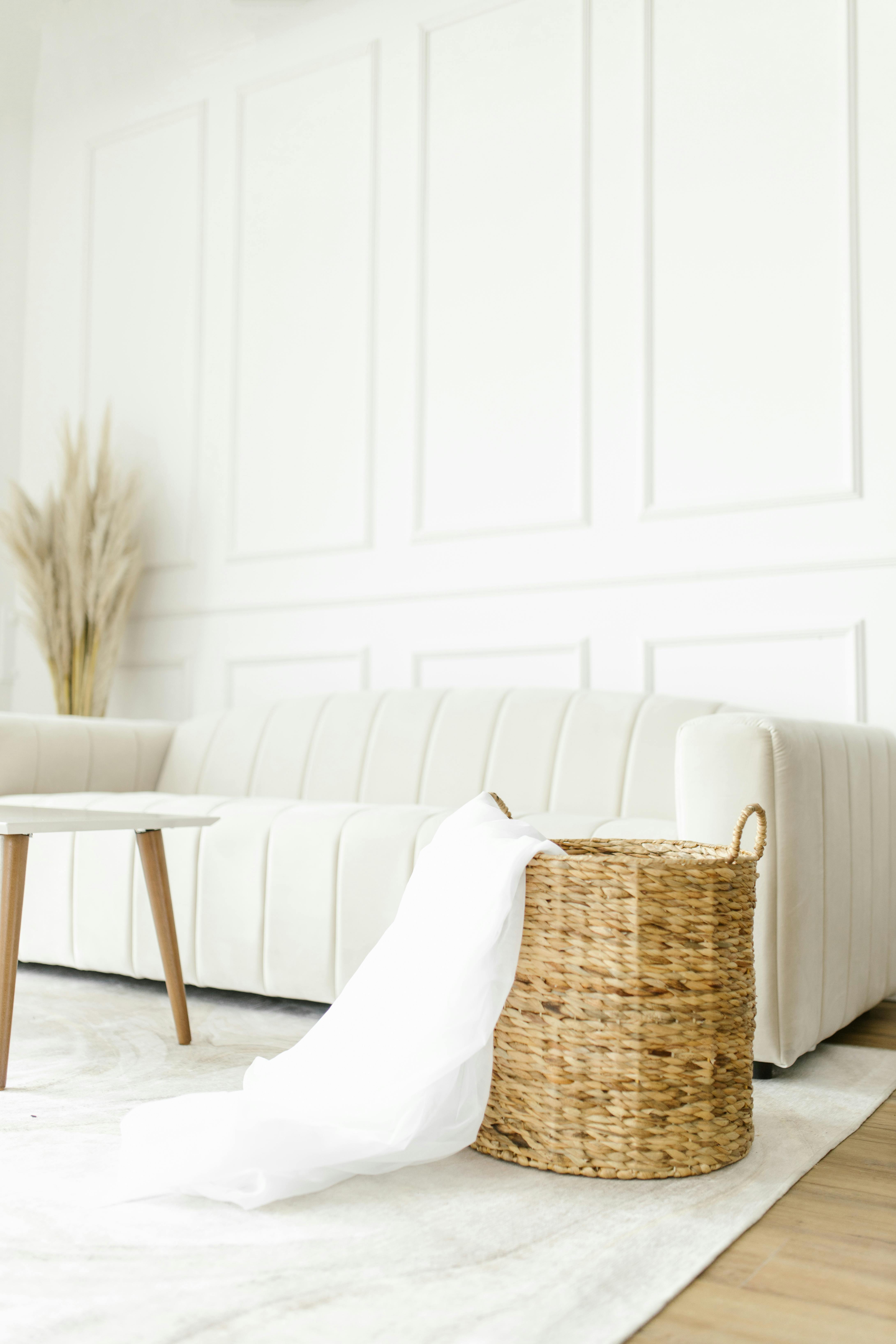Bright minimalist interior with a white sofa and wicker basket accenting the natural decor.