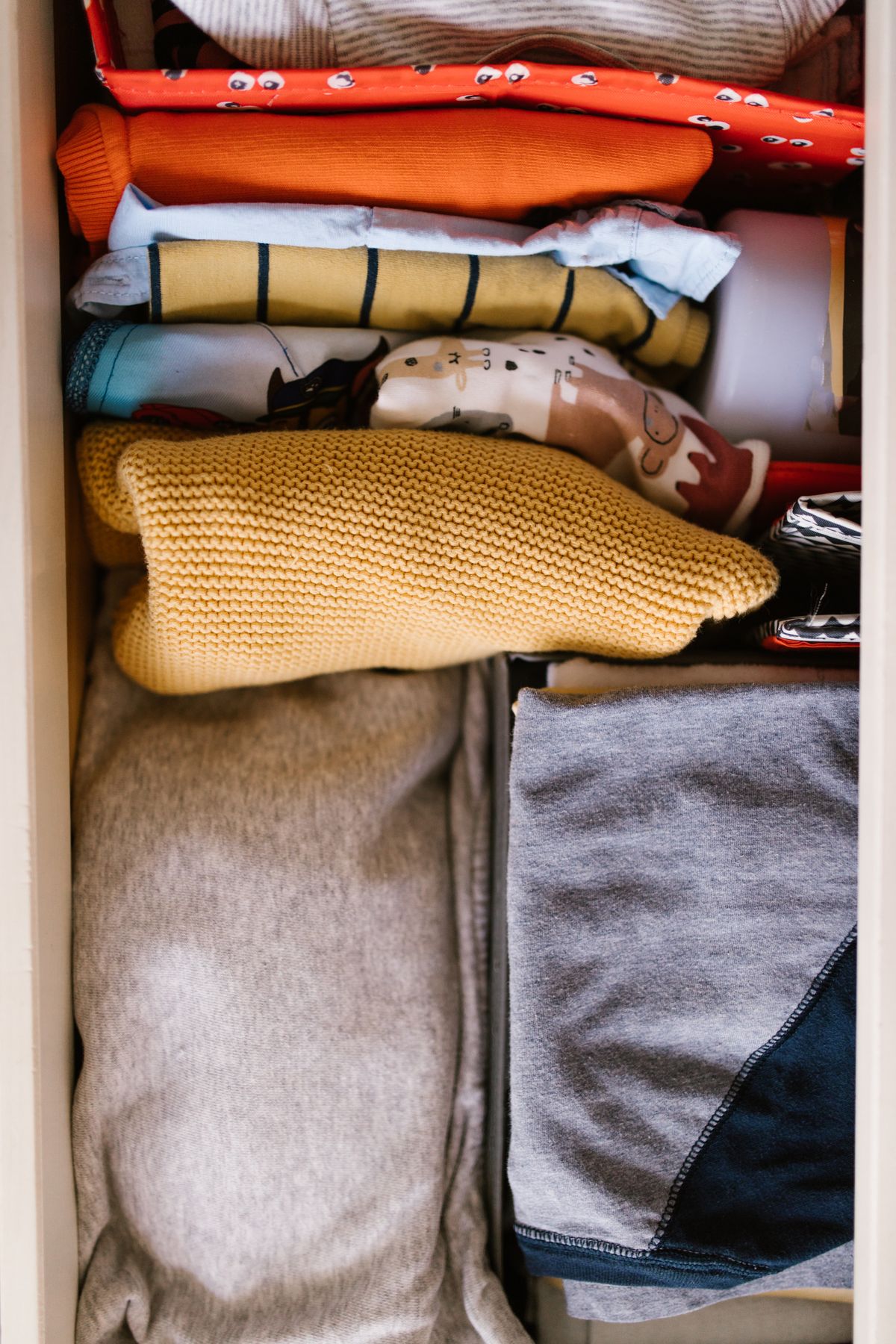 Colorful clothes folded upright in neat rows inside an organized dresser drawer, viewed from above