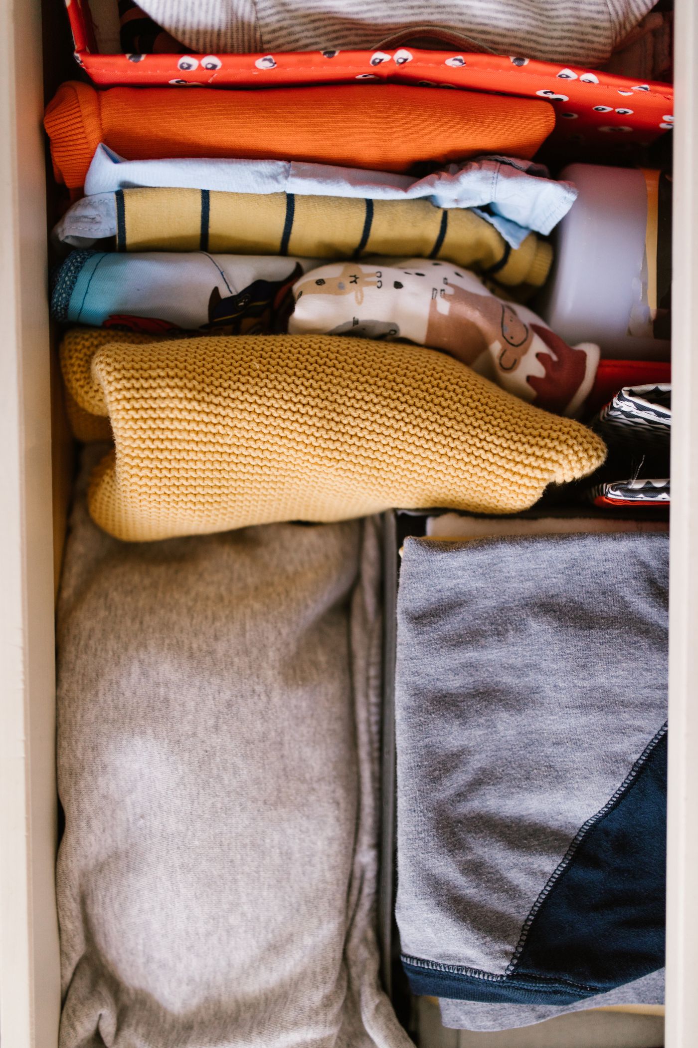 Colorful folded clothes neatly arranged in a drawer without people