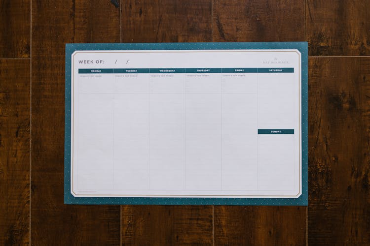 A Weekly Organizer On A Wooden Surface