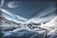 山间湖泊白雪皑皑，倒映着天空，冬日风景宁静