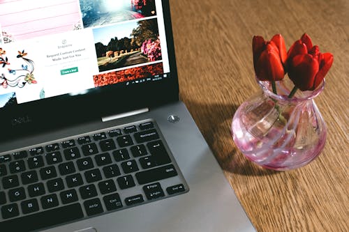 Black Dell Laptop Beside the Pink Glass Vase