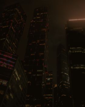A dramatic night view of illuminated skyscrapers in Moscow's city center.