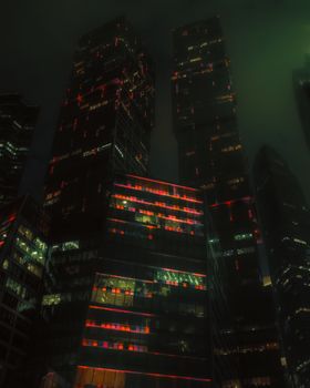 Dramatic view of Moscow City skyscrapers with colorful lights against a night sky.