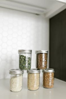 Five glass jars filled with food items arranged neatly on a shelf.