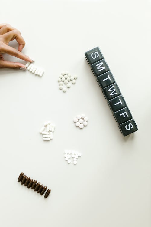 Pills and a Medicine Container on White Surface 