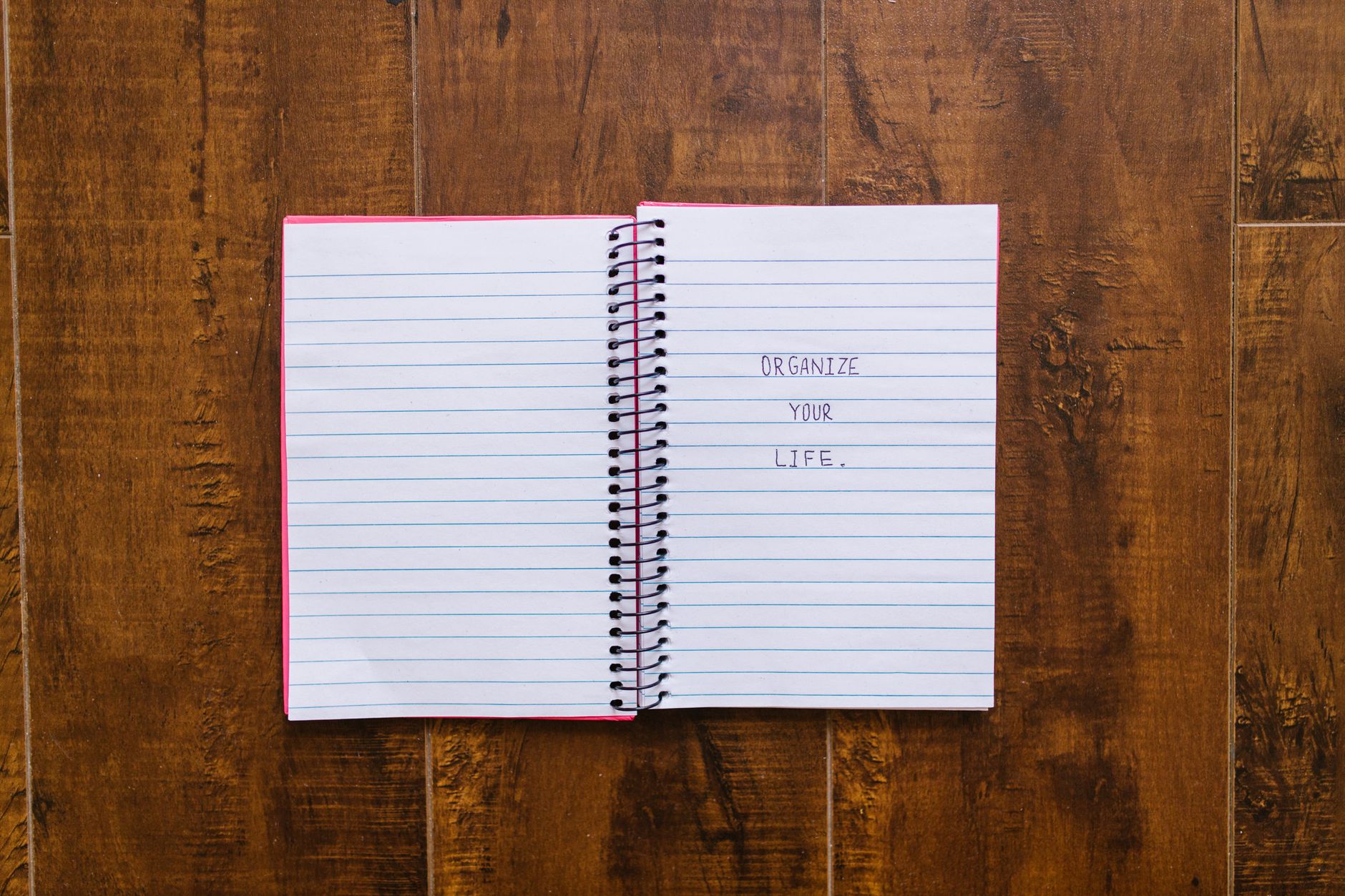 Open notebook with 'Organize Your Life' written, placed on wooden surface.