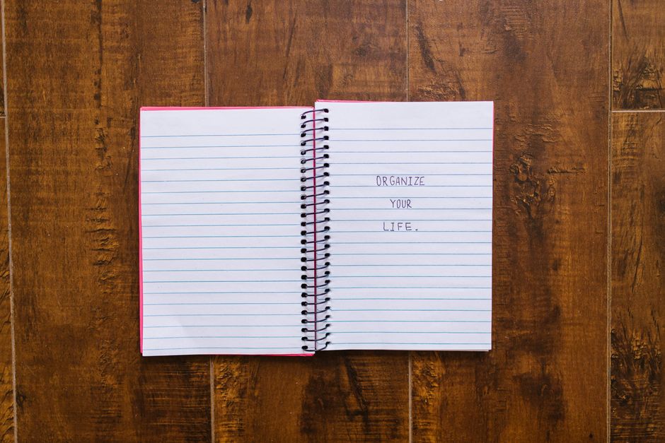 Open notebook with 'Organize Your Life' written, placed on wooden surface.