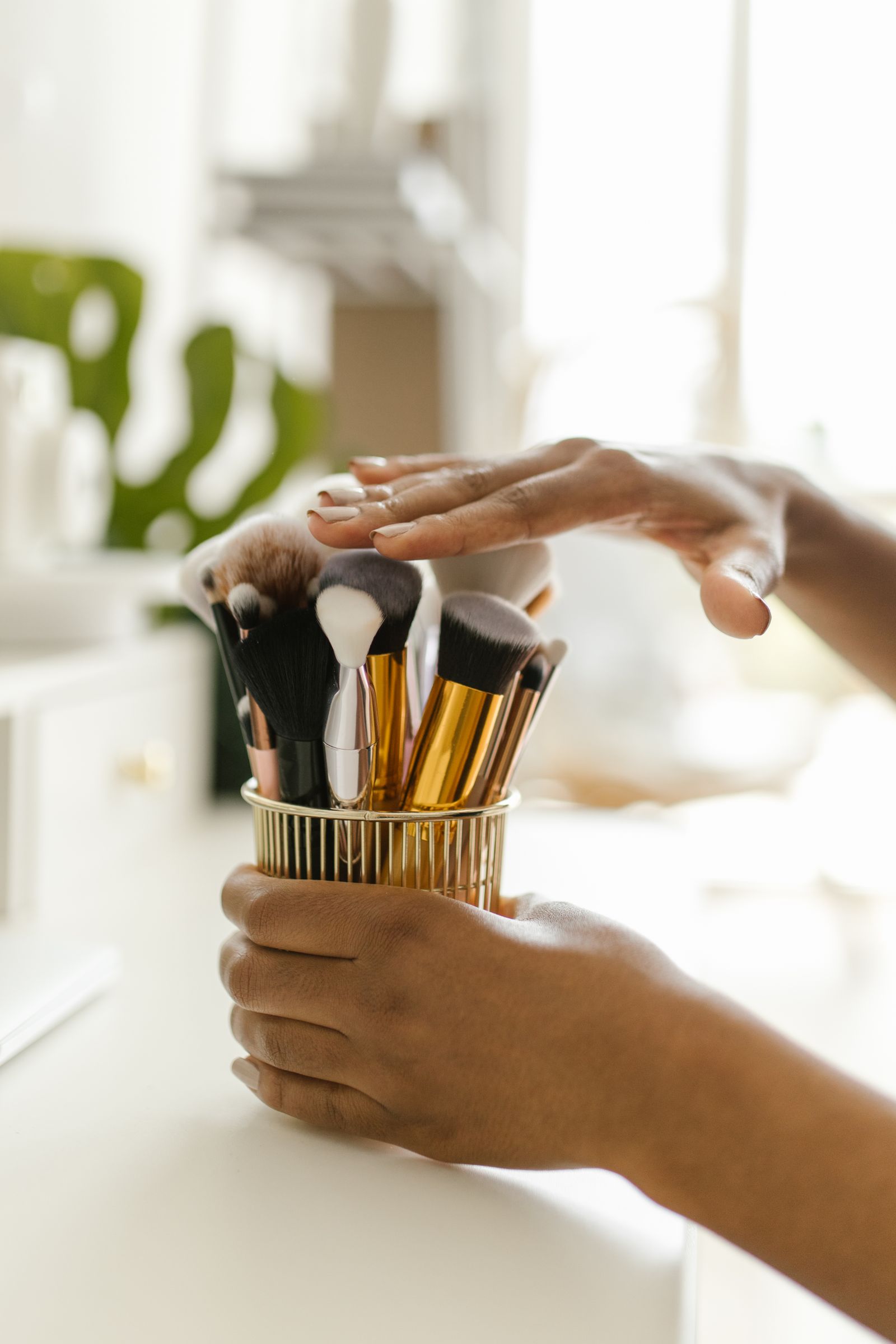 Hands organizing makeup brushes in a refined beauty tool holder