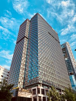 Photo of a modern skyscraper in Seoul, showcasing unique architectural design against a vibrant blue sky.