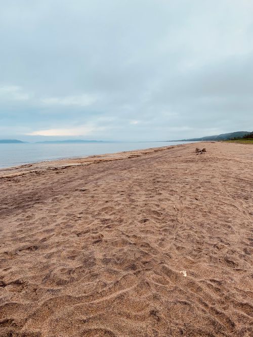 Free A tranquil view of an empty sandy beach with a cloudy sky overhead, perfect for relaxation. Stock Photo