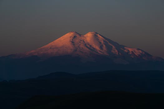 Majestic snowcapped mountain in warm sunrise light, creating a serene and awe-inspiring view.