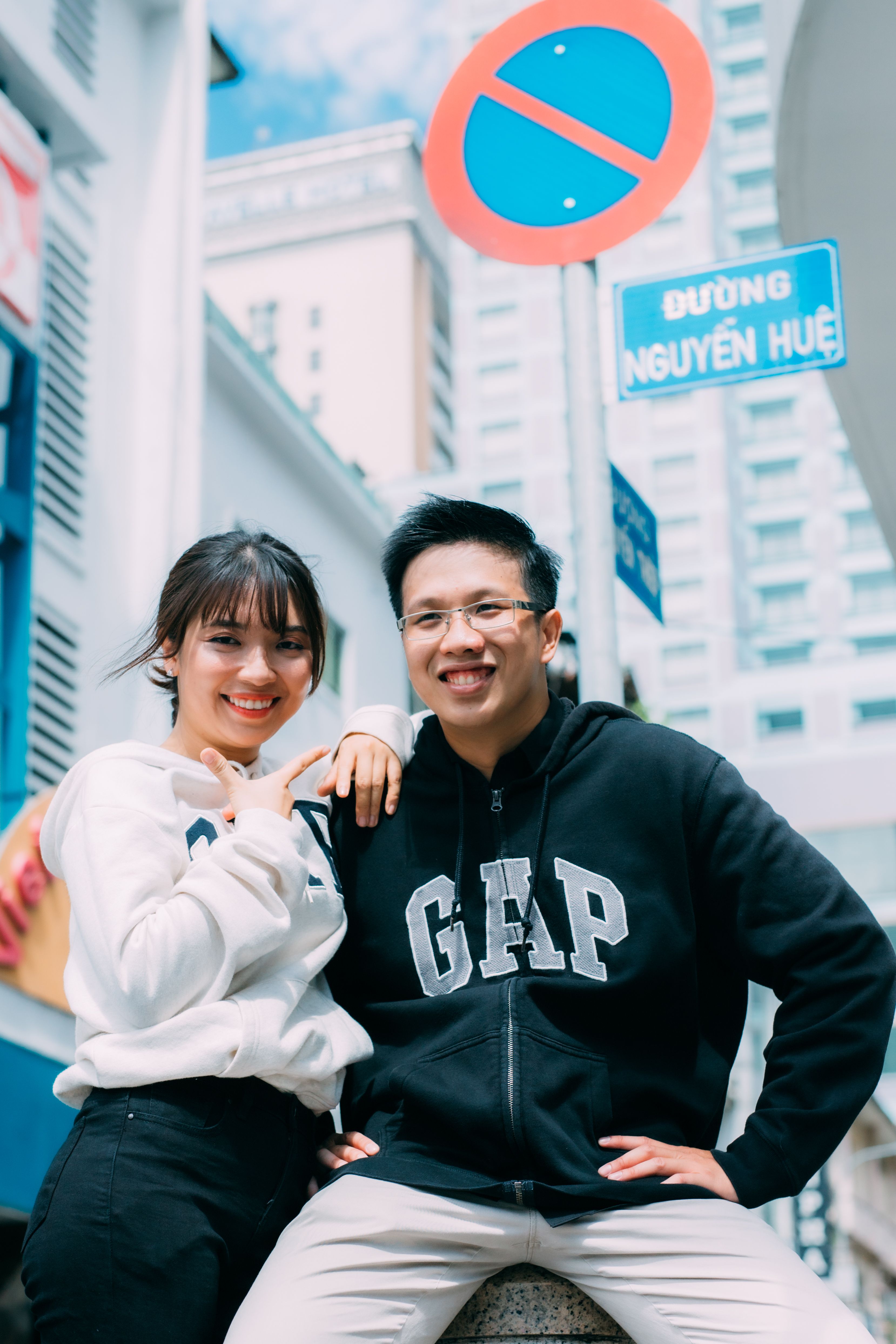 Smiling couple posing in trendy hoodies on Nguyen Hue street.