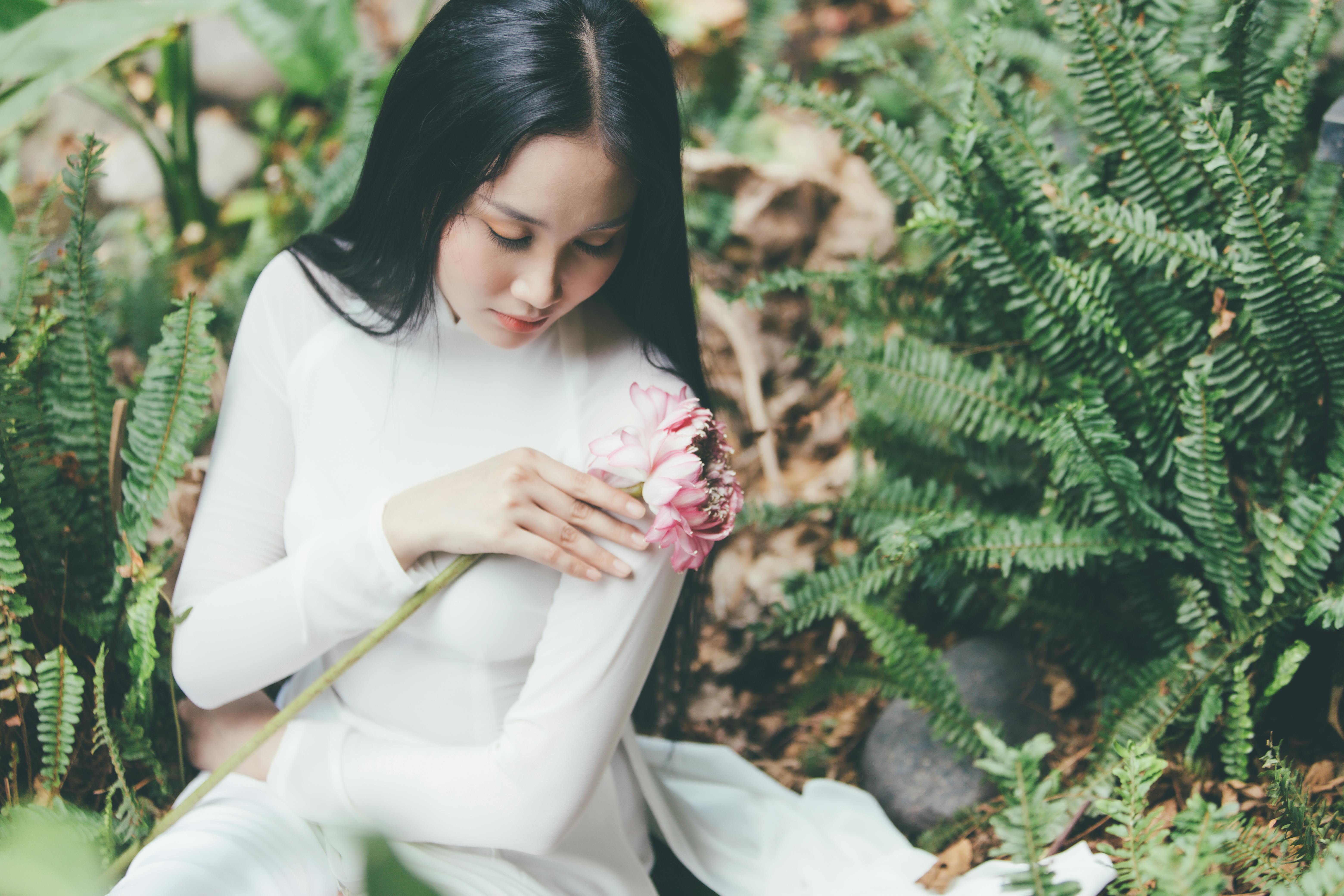 young girl in white outfit holding pink flower