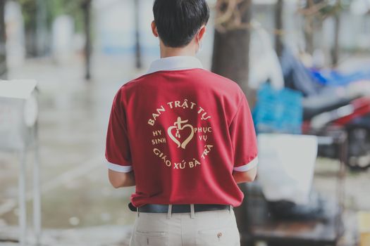 Man wearing a red t-shirt with text outdoors on a rainy day.