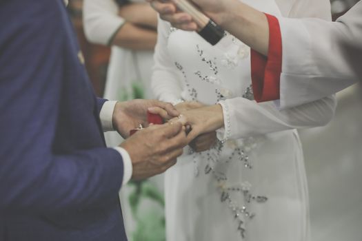 Close-up of a couple exchanging rings during a wedding ceremony indoors.