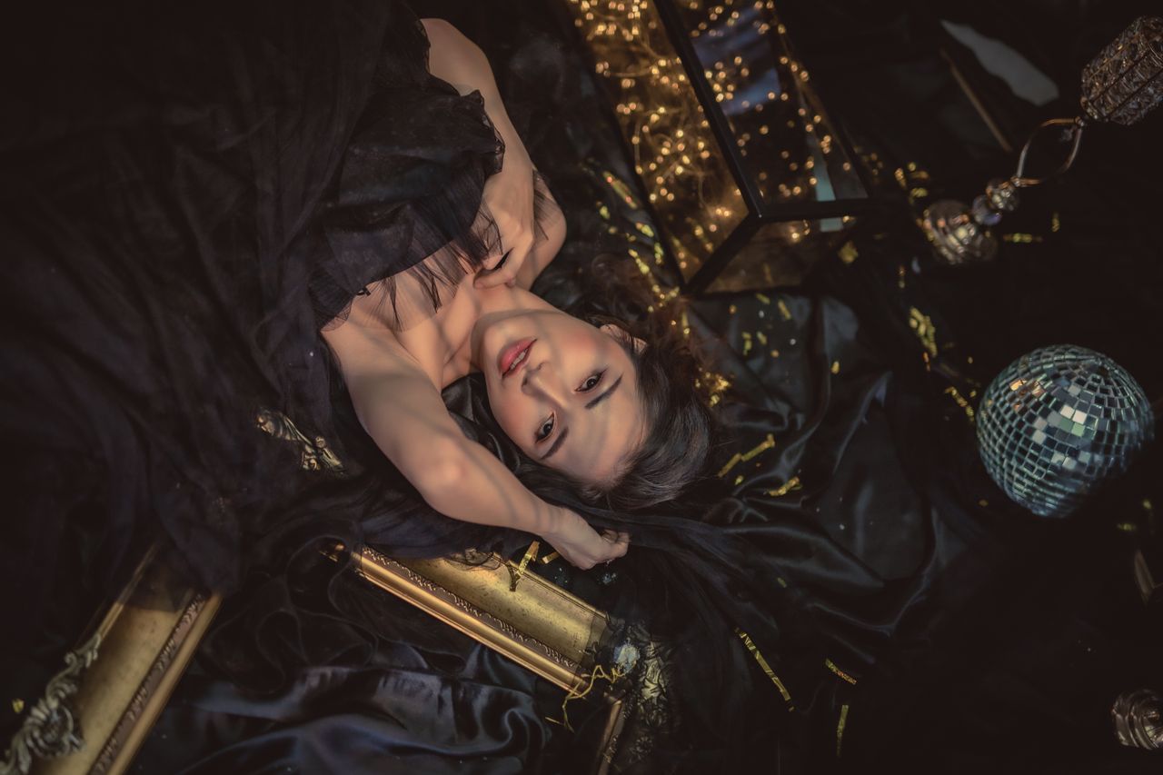 artistic portrait of a woman lying amid black fabric with golden accen