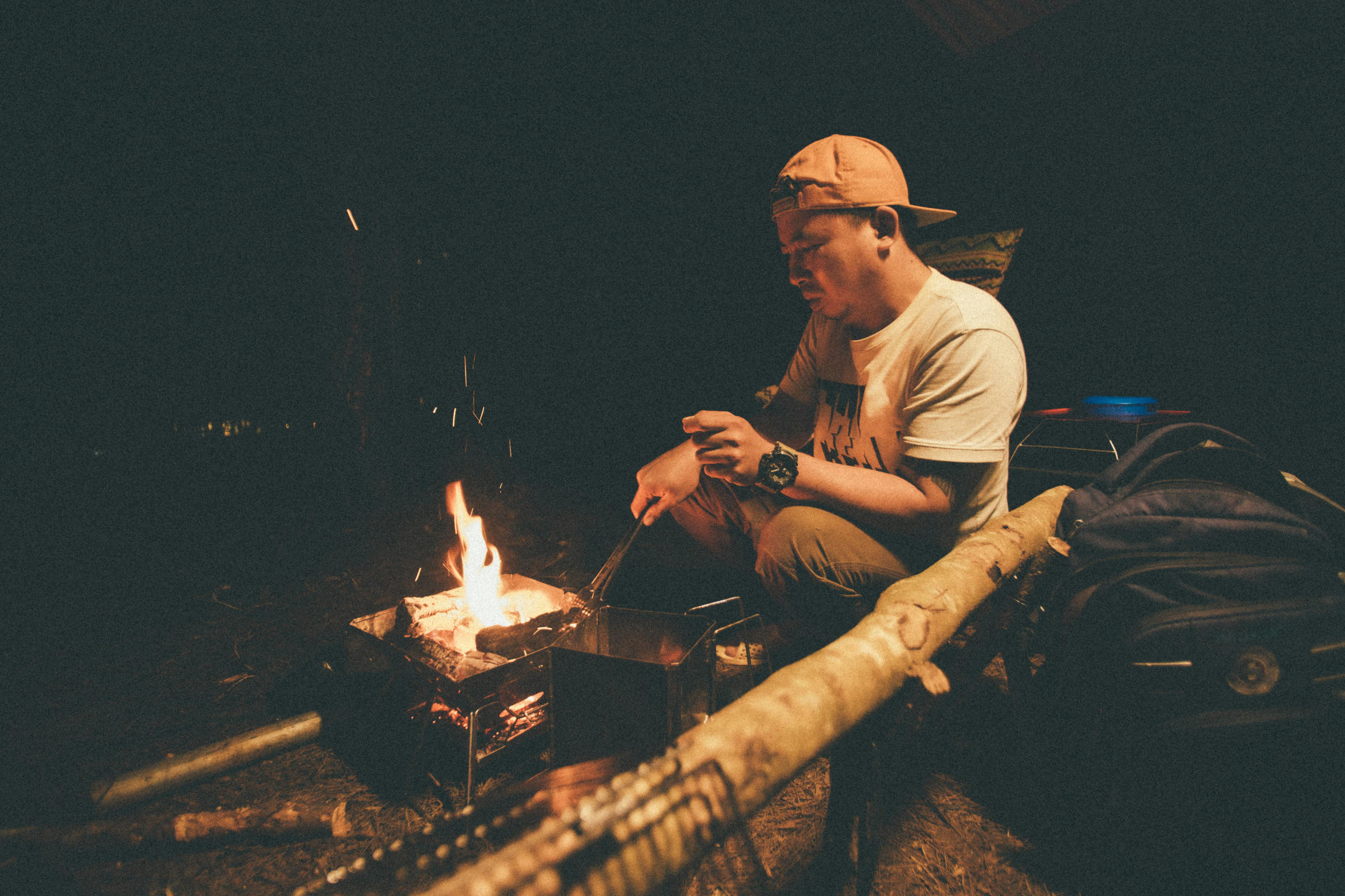 a man squatting in front of the fire pit