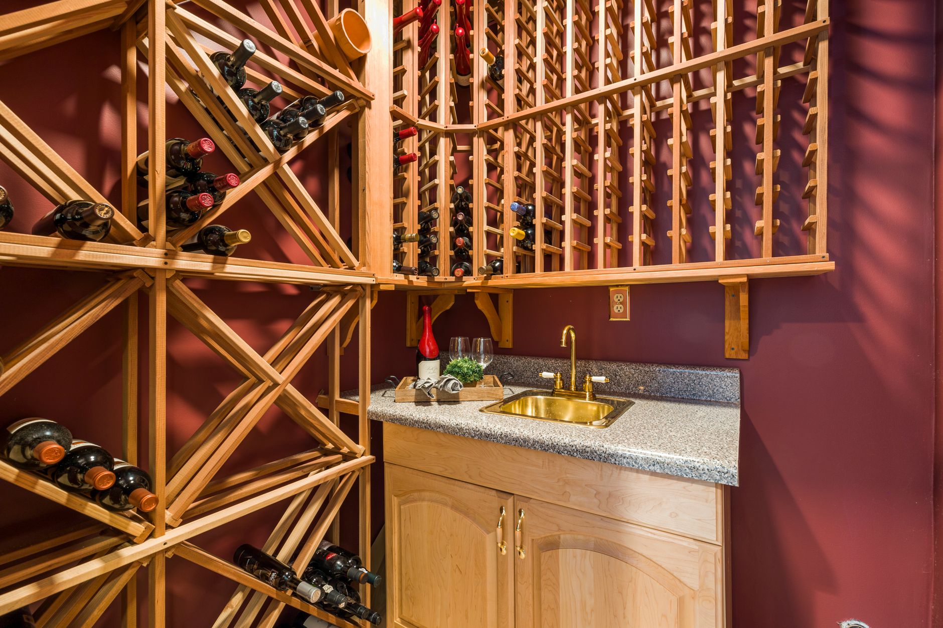 Stylish indoor wine cellar with wooden racks and a granite countertop sink.