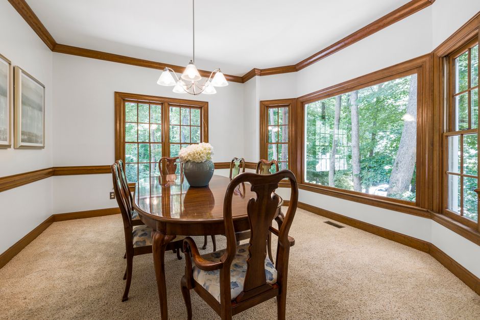 Traditional dining room interior featuring wooden furniture and large picture windows.