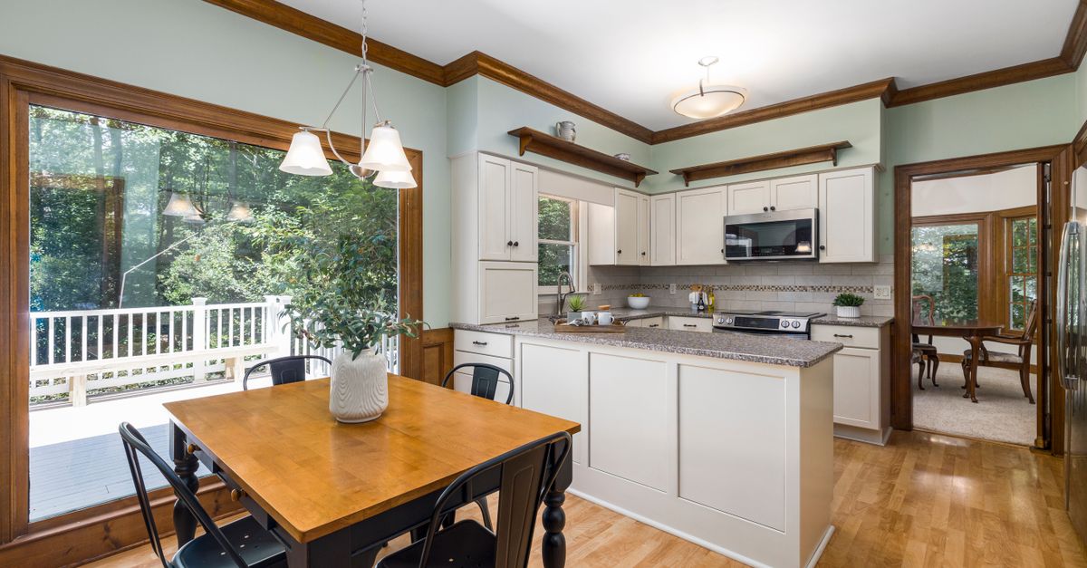 Bright and spacious kitchen with natural lighting, wooden accents, and modern white cabinetry.