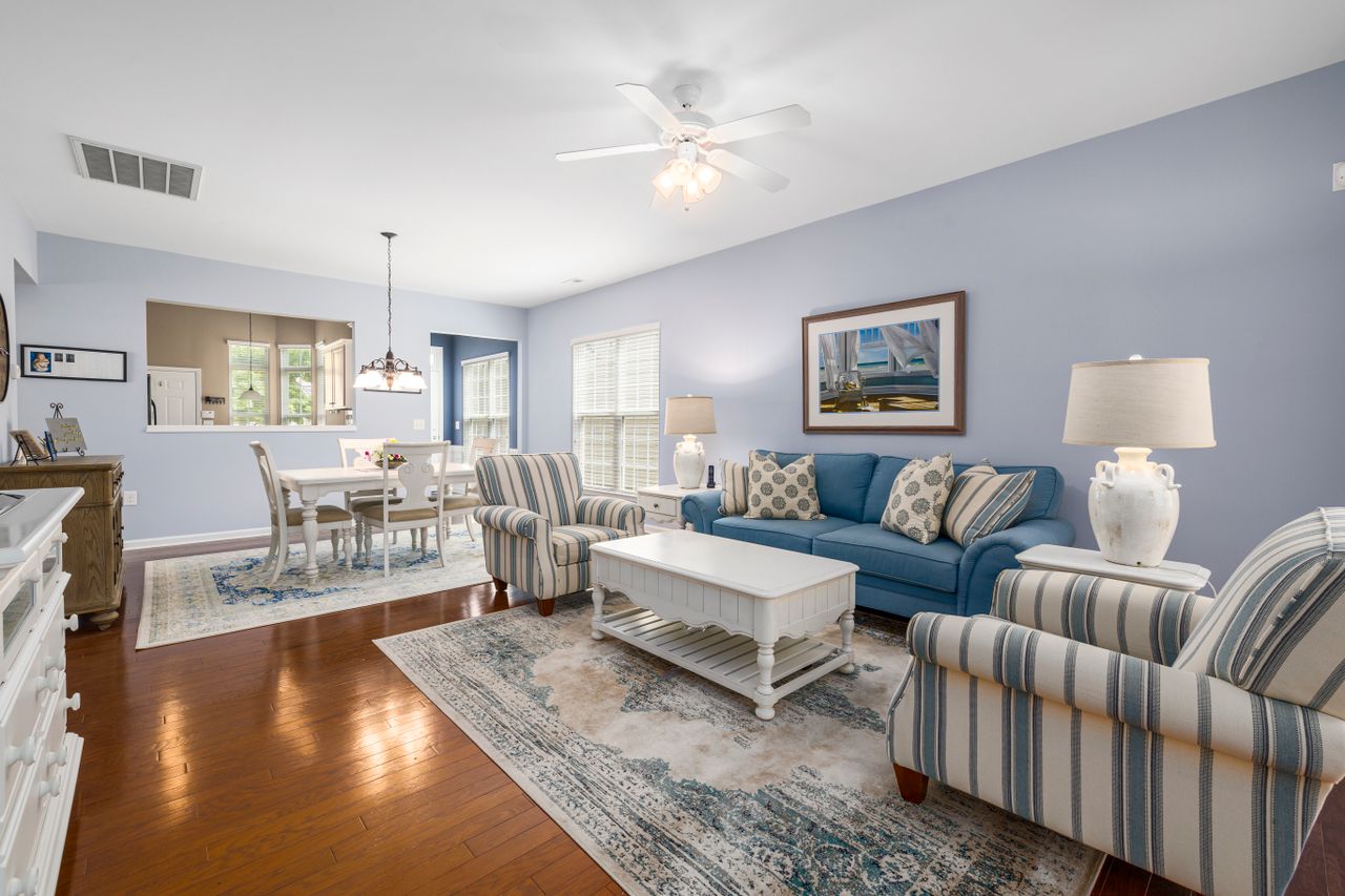 Coastal living room with blue sofa, striped armchairs, white coffee table, and beach wall art