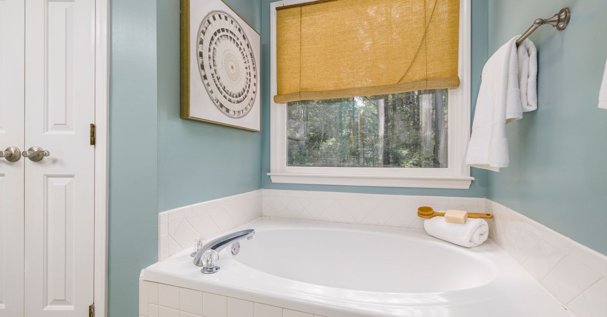 Bright bathroom with a stylish bathtub, towels, and natural light through a window.