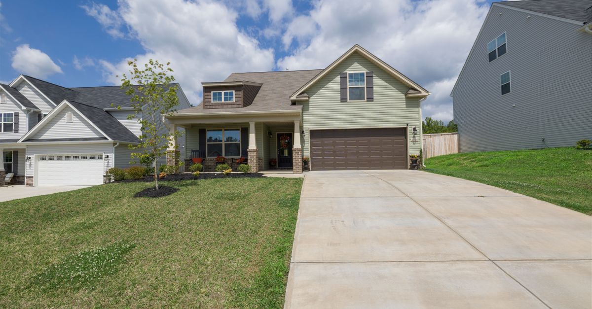 A modern suburban detached house with a spacious driveway under a bright blue sky.