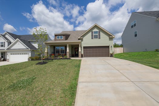 A modern suburban detached house with a spacious driveway under a bright blue sky.