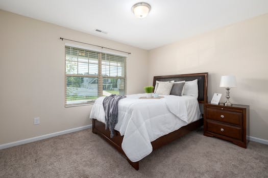 A stylish minimalist bedroom with a comfortable bed and wooden furniture.