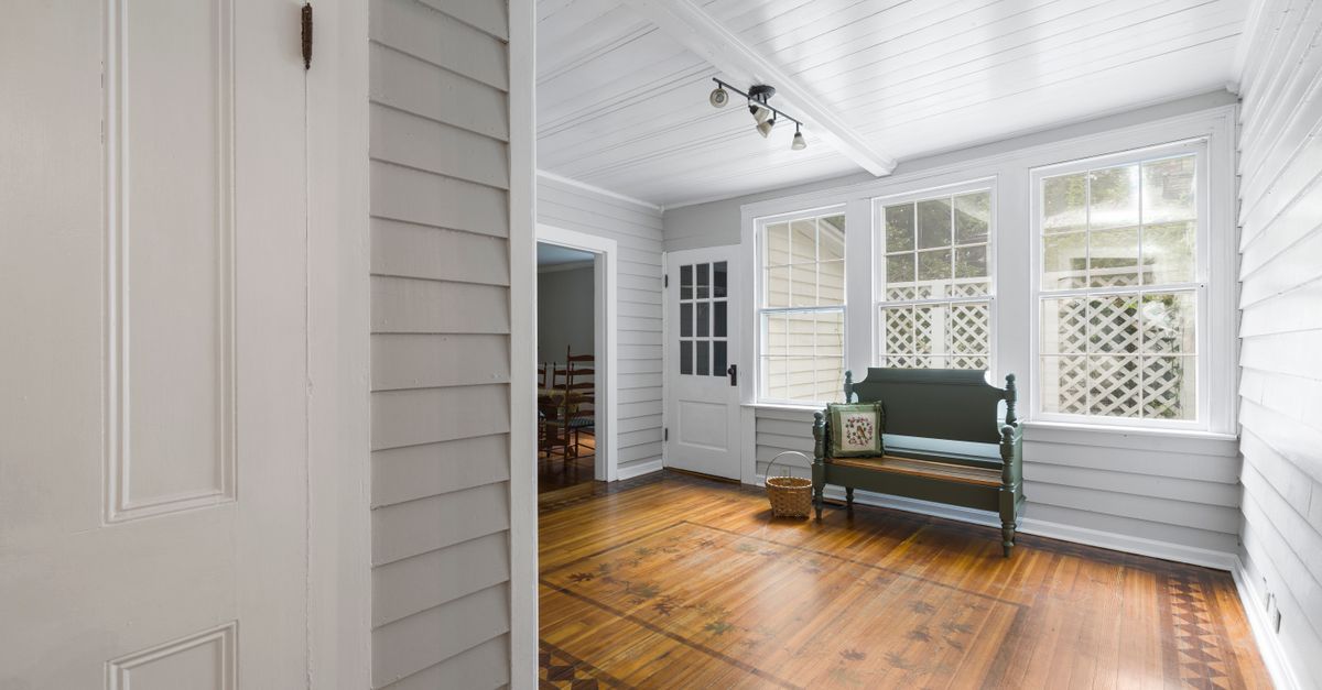 Bright interior of a sunlit porch with a classic wooden bench and elegant flooring.