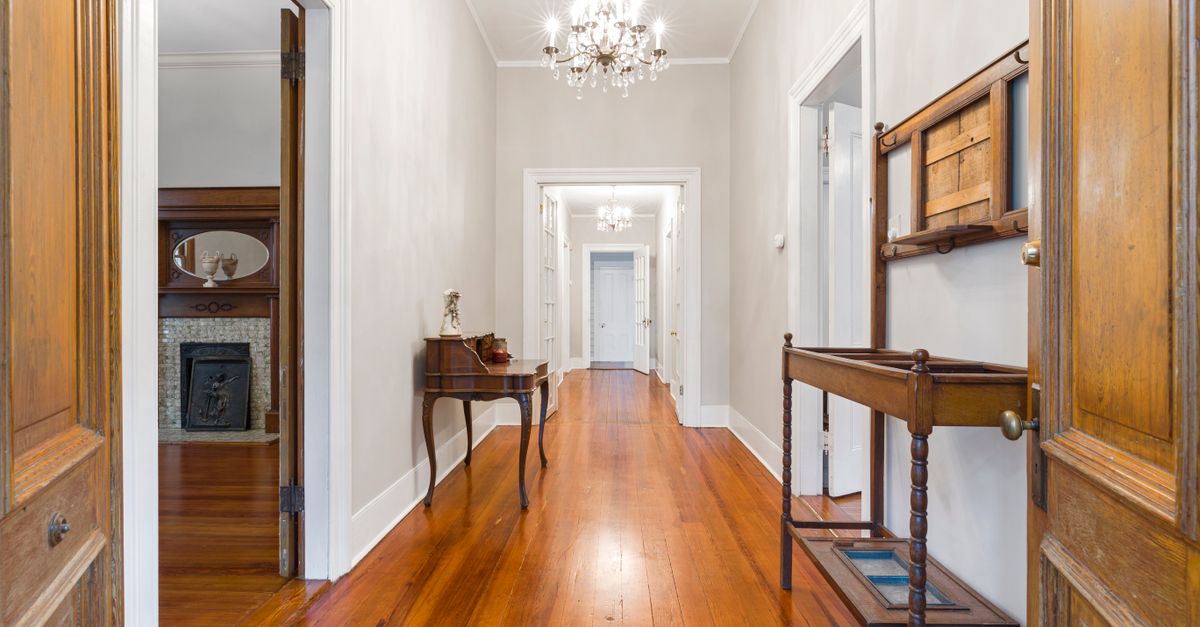 Spacious hallway showcasing elegant interior design with wooden floors and chandeliers.