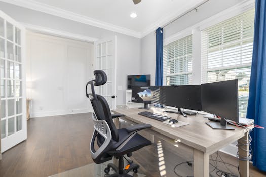 Brightly lit home office featuring an ergonomic chair, dual monitors, and a spacious desk setup for productivity.