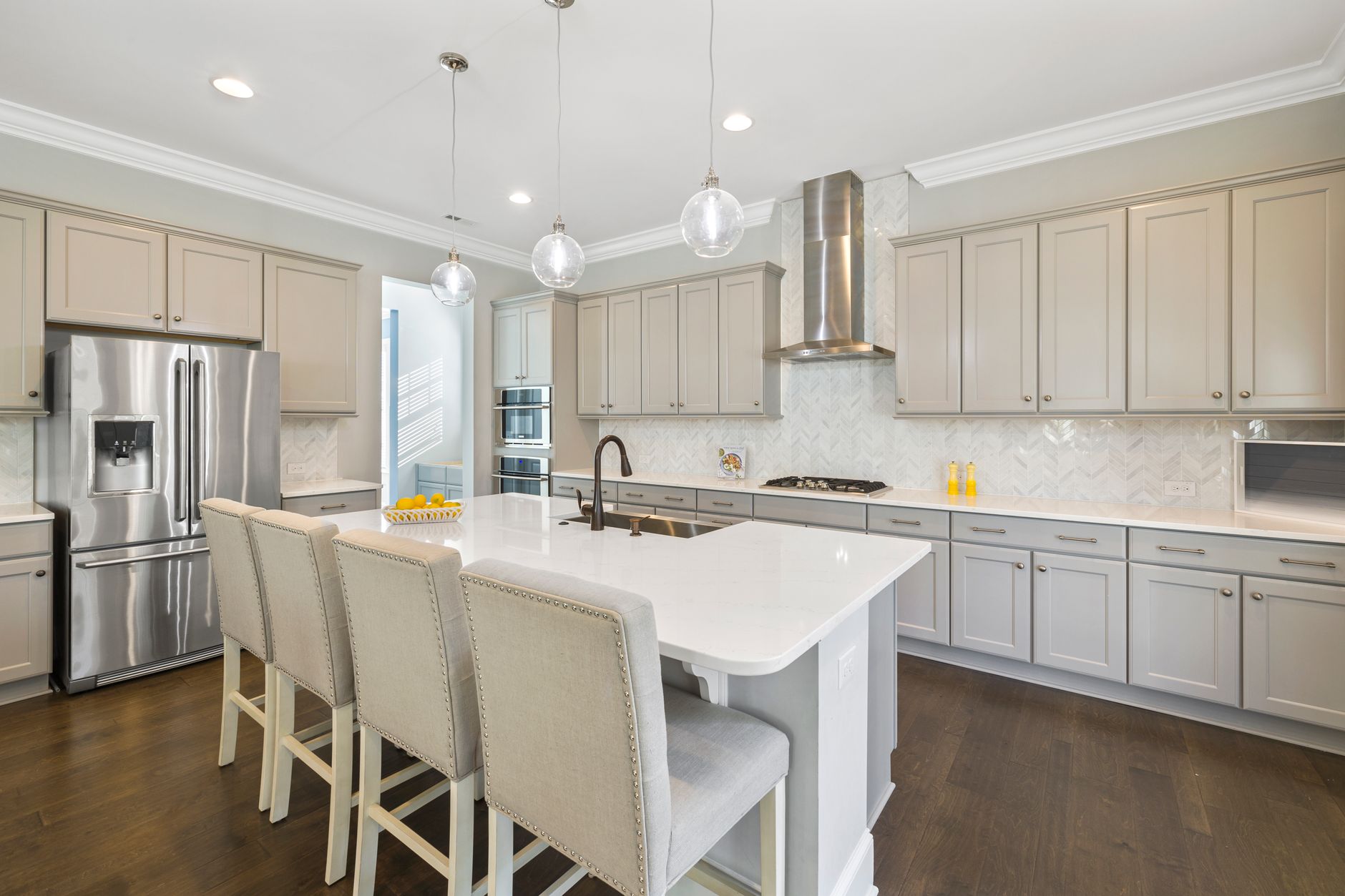 Bright modern kitchen with white cabinets, a centre island, pendant lighting, and stainless steel appliances.