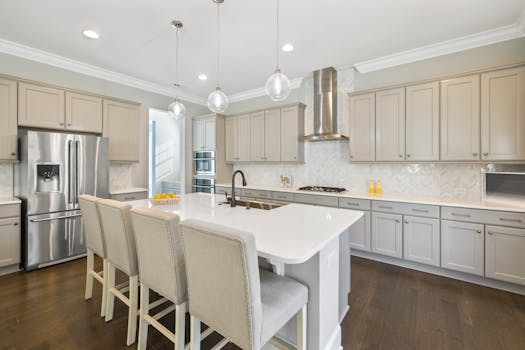 Elegant modern kitchen featuring a central island, stainless steel appliances, and stylish pendant lights.