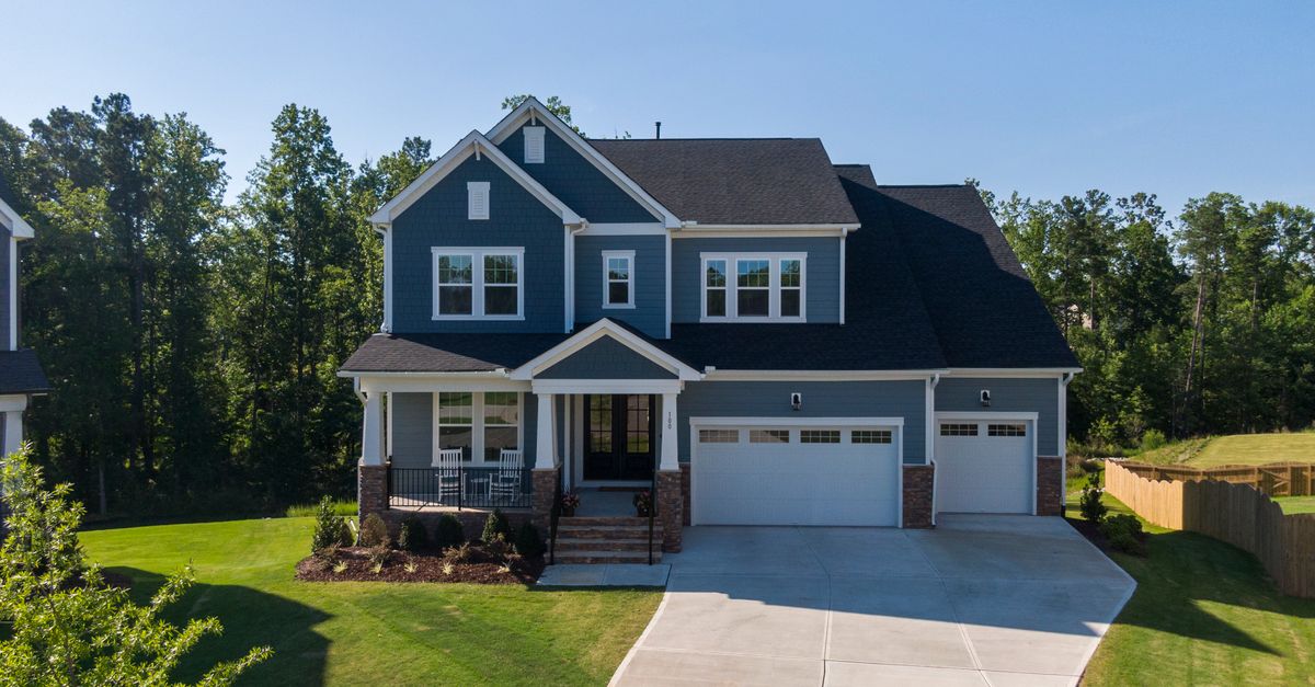 Charming suburban house in Holly Springs, NC, featuring a large driveway and porch.