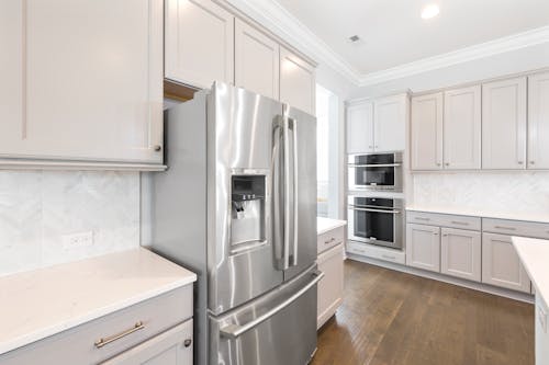Silver Refrigerator beside White Kitchen Cabinets