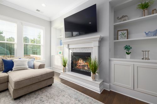 Free Contemporary living room featuring a fireplace, large windows, and modern decor for a cozy ambiance. Stock Photo