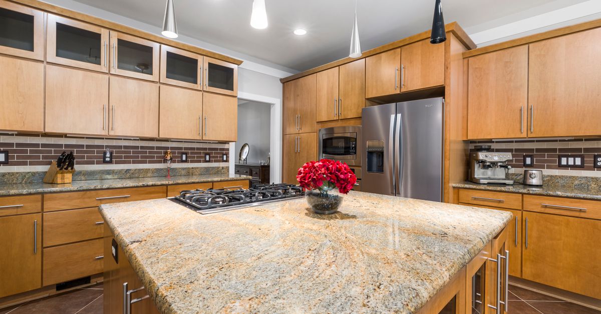 A spacious modern kitchen featuring a sleek marble island and central red flower arrangement.