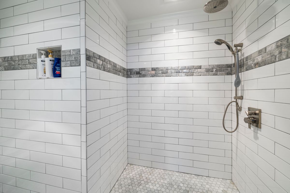 dark modern wet room with black tiles and glass screen