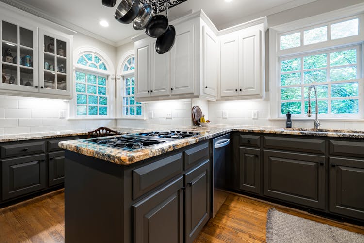 White Wooden Kitchen Cabinets And A Marble Counter Top